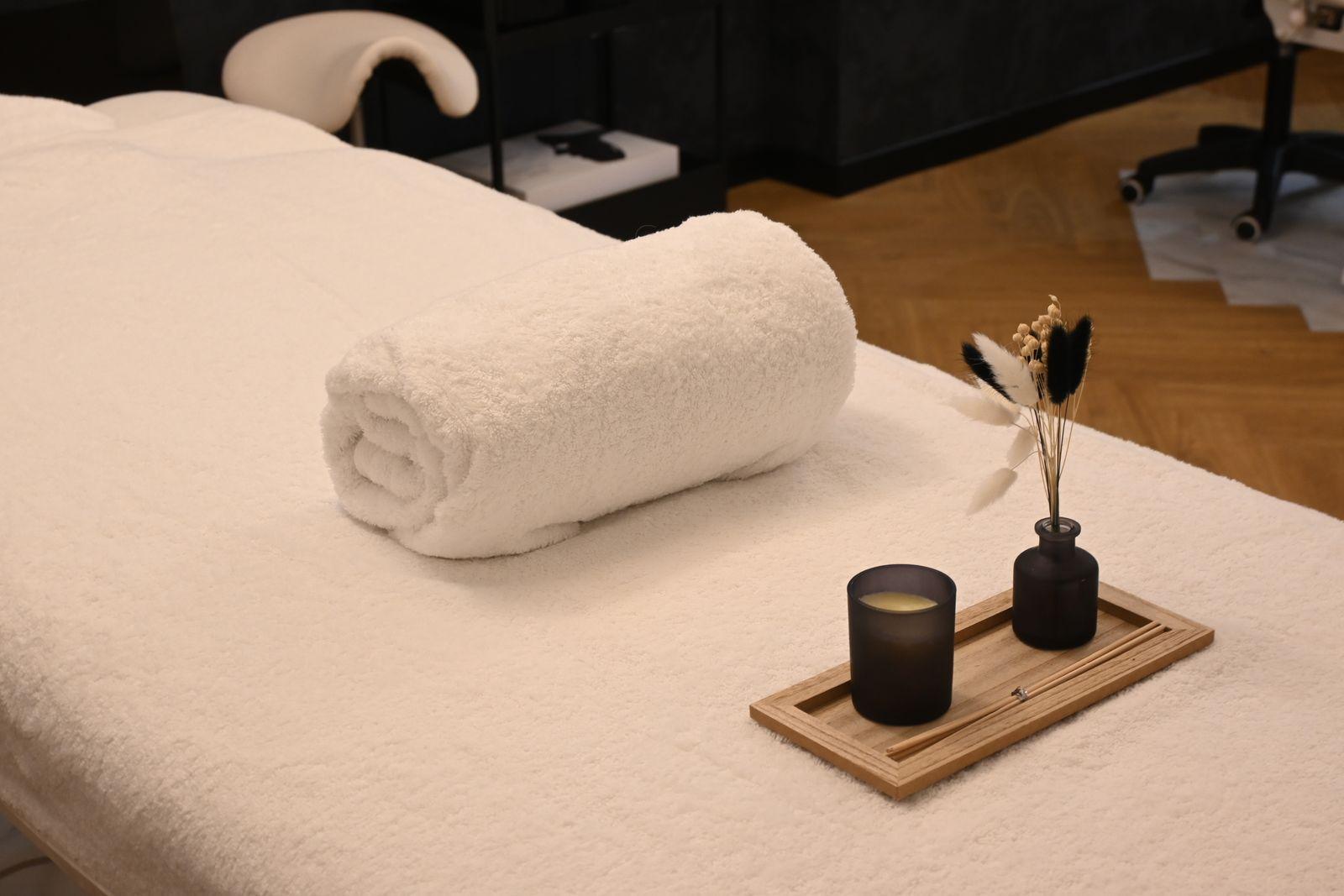 A prepared massage table with a rolled towel, candle, and dried flowers