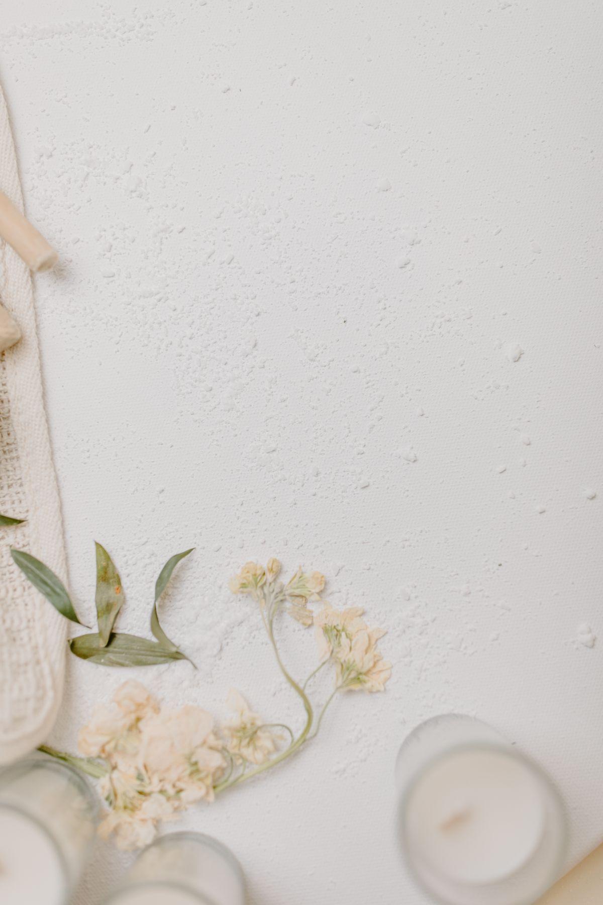 Dried flowers and candles on a textured white surface