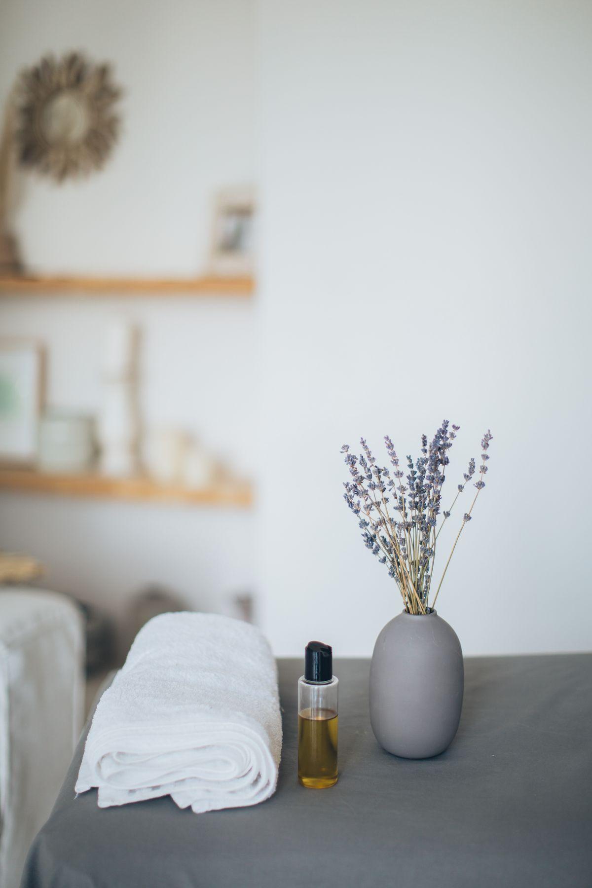 Massage oil bottle beside lavender and a folded towel