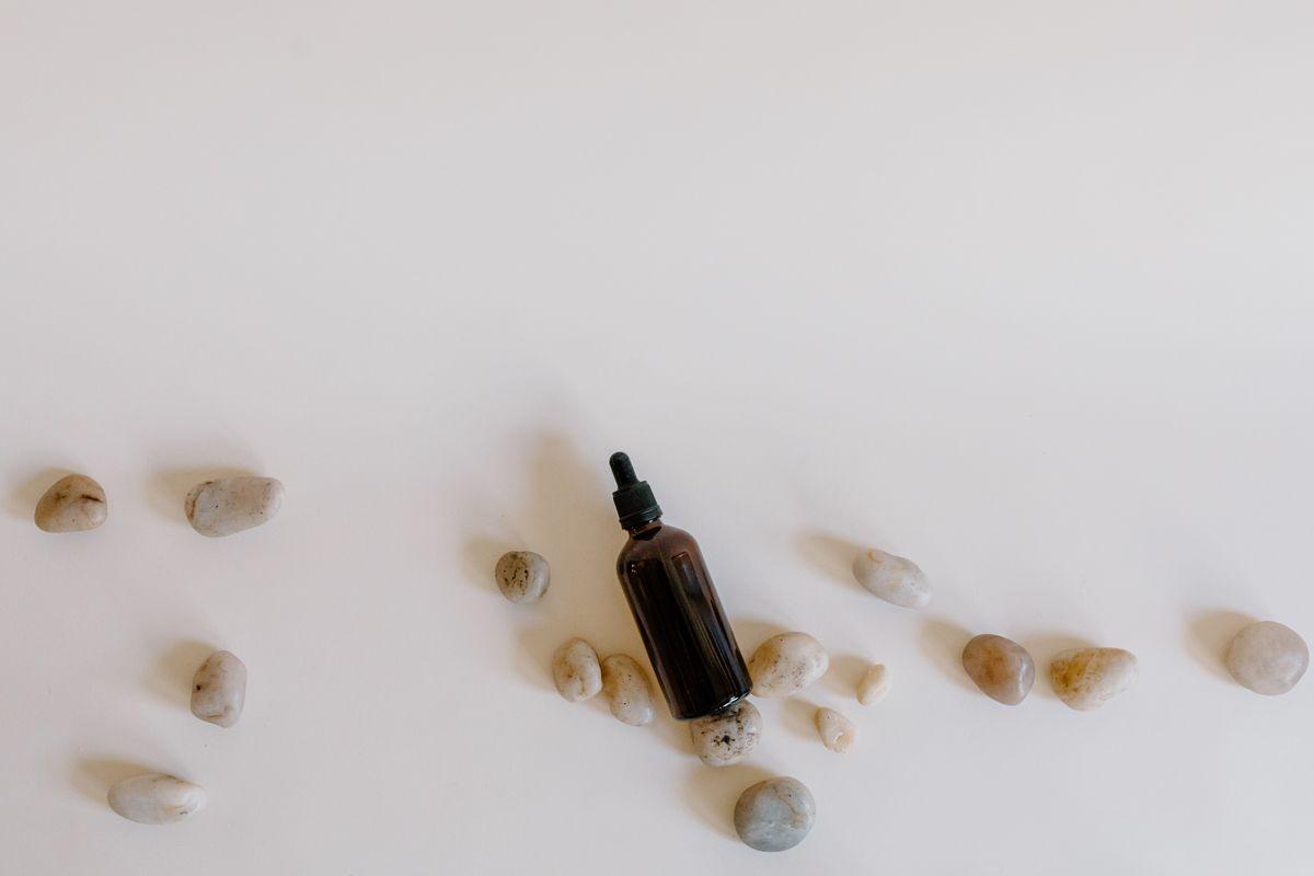 Amber dropper bottle surrounded by smooth stones