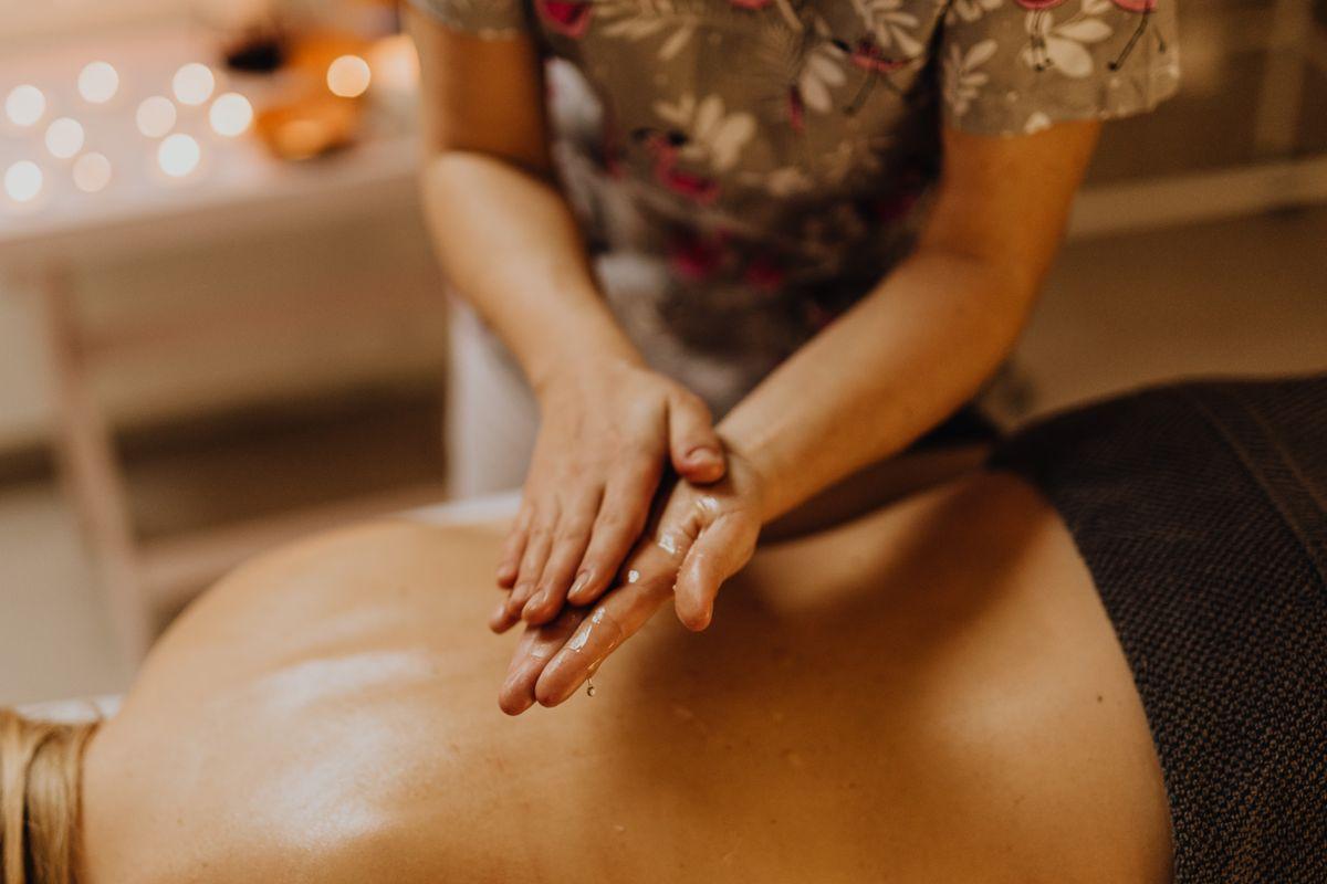 Hands massaging an oiled back in warm candlelight